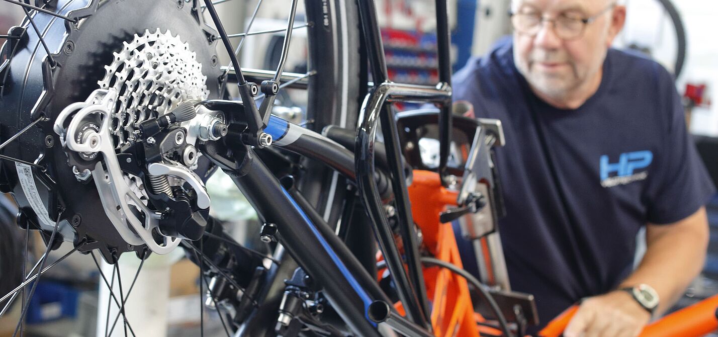 Ein Fahrradmechaniker arbeitet in seiner Werkstatt an der Nachrüstung eines Elektrofahrrads.